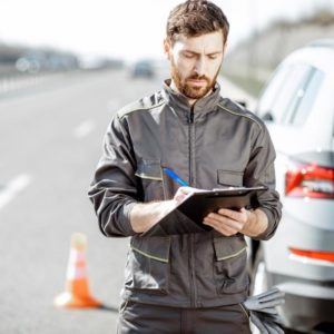 A man signs documents at roadside after a motorcycle accident.