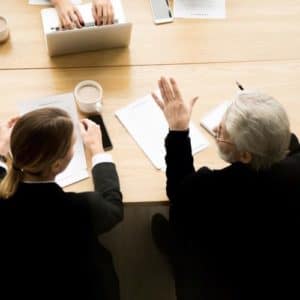 A lawyer and his female client are shown in the middle of mediation with an employer during a gender discrimination case.