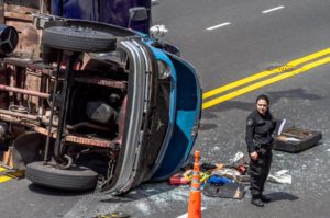 A police officer directs traffic after a semi-truck accident.