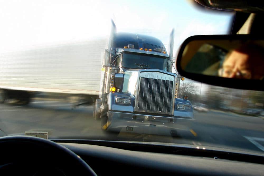 A semi-truck is about to run head on into a car, image shown from car drivers perspective.