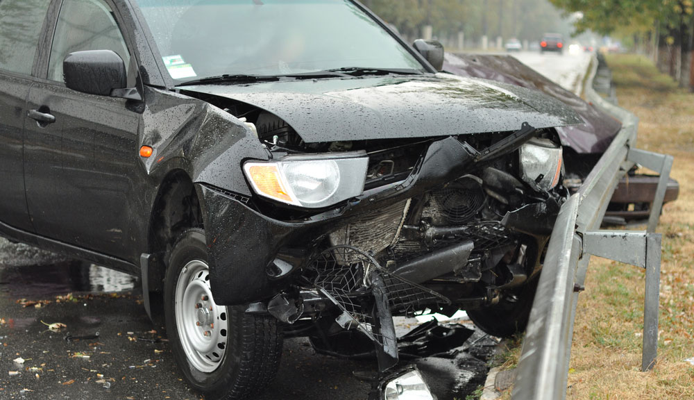 A black SUV that has ran into a guard rail.