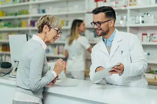 pharmacist giving older lady medicine.