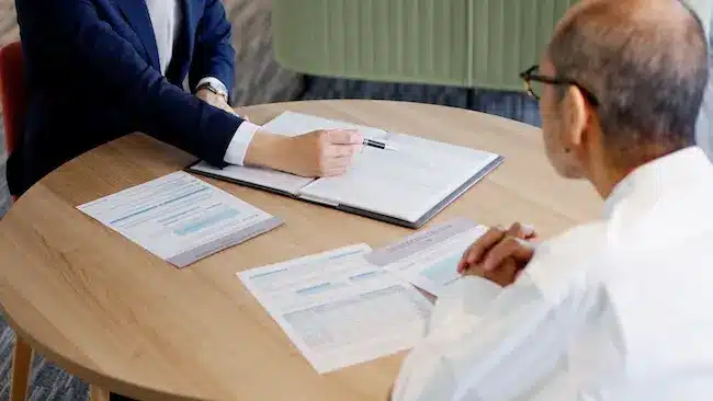 A personal injury attorney is conducting a liability determination assessment with the client reviewing accident documentation and fault percentages.